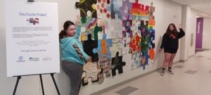 Woman standing next to puzzle piece art display